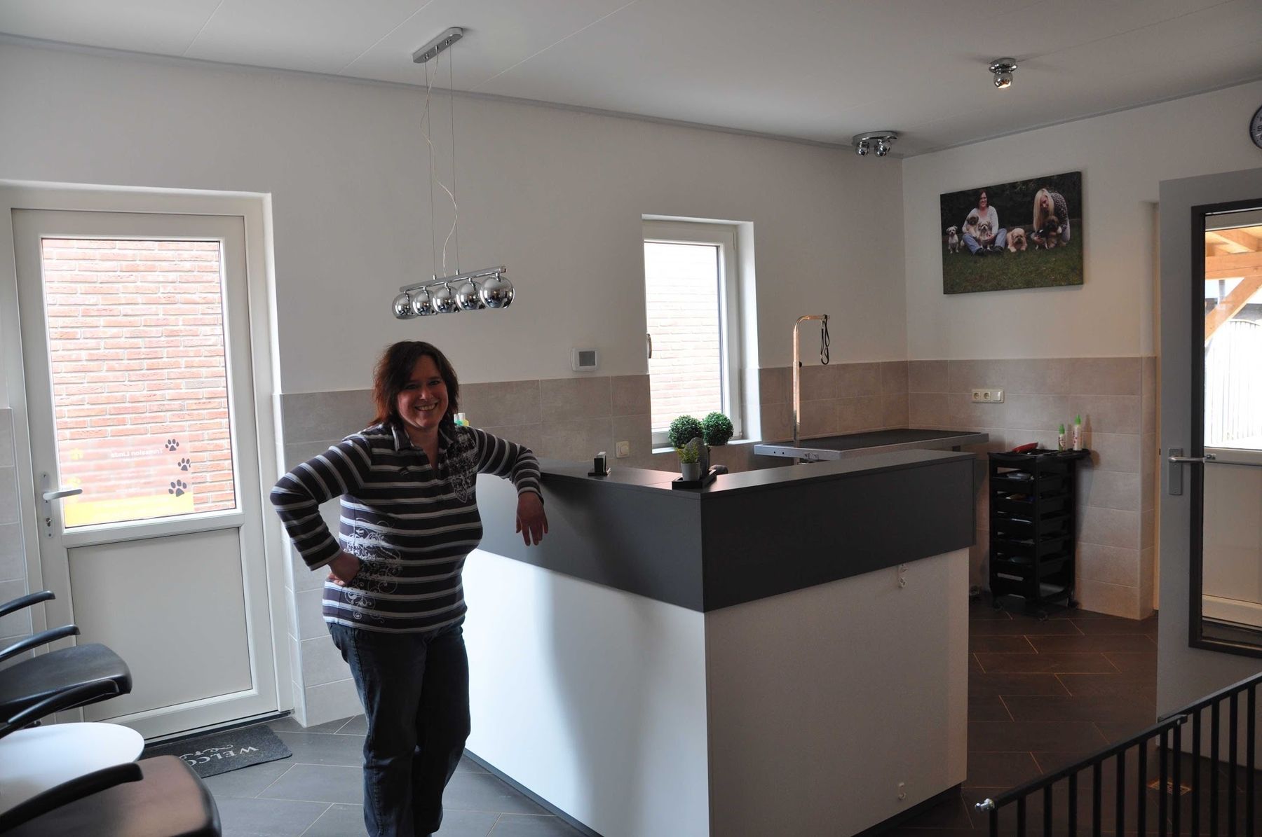 Linda in haar trimsalon aan de balie, met de deur naar de tuin